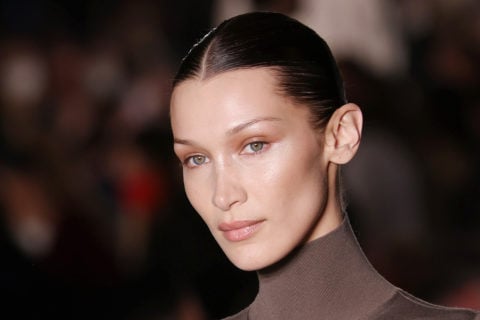Bella Hadid walks the runway wearing a brown turtleneck top and with her hair in a slicked-back bun
