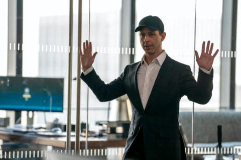 a still from the tv show succession of kendall roy wearing a white dress shirt, dark blazer and black baseball hat