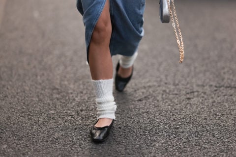 A photo of a person wearing white leg warmers with black ballet flats